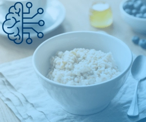 A white bowl of oatmeal on a cloth napkin next to a spoon. In the background, there's a cup, honey, and blueberries. A brain icon is overlayed.