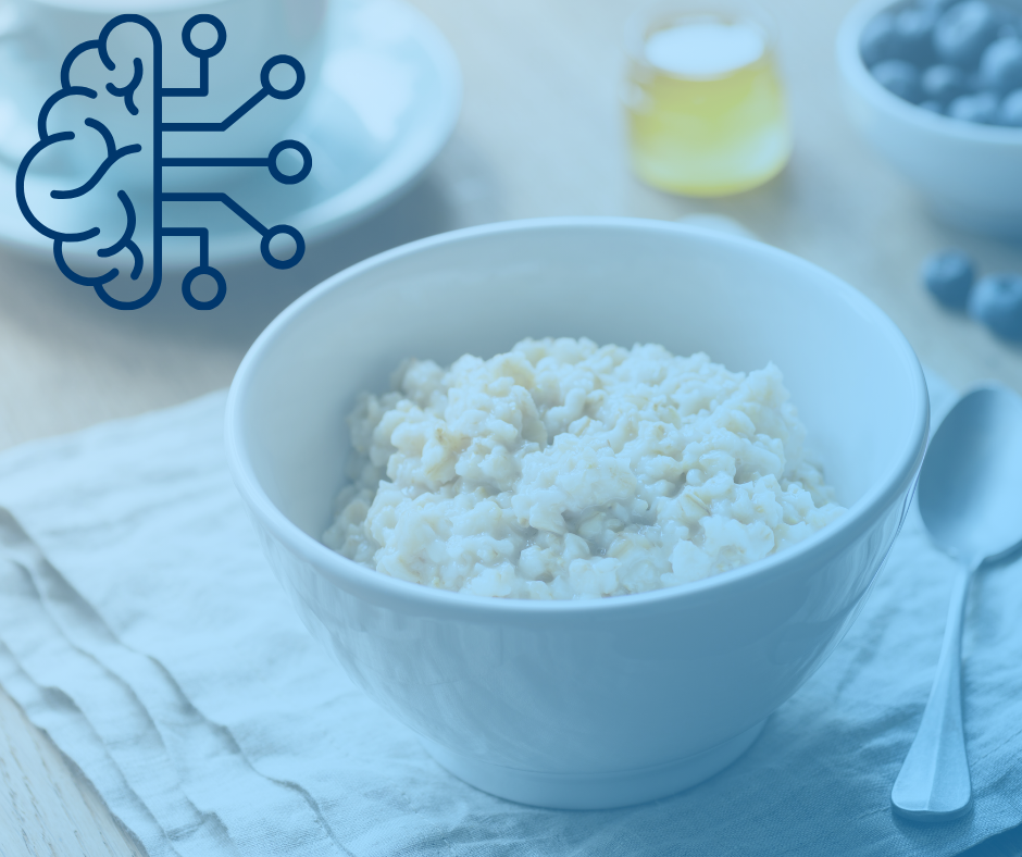 A white bowl of oatmeal on a cloth napkin next to a spoon. In the background, there's a cup, honey, and blueberries. A brain icon is overlayed.